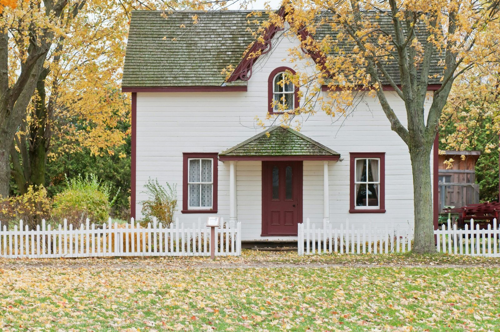 Mortgage Protection Picturesque traditional house with autumn foliage and a white picket fence in London, Ontario.