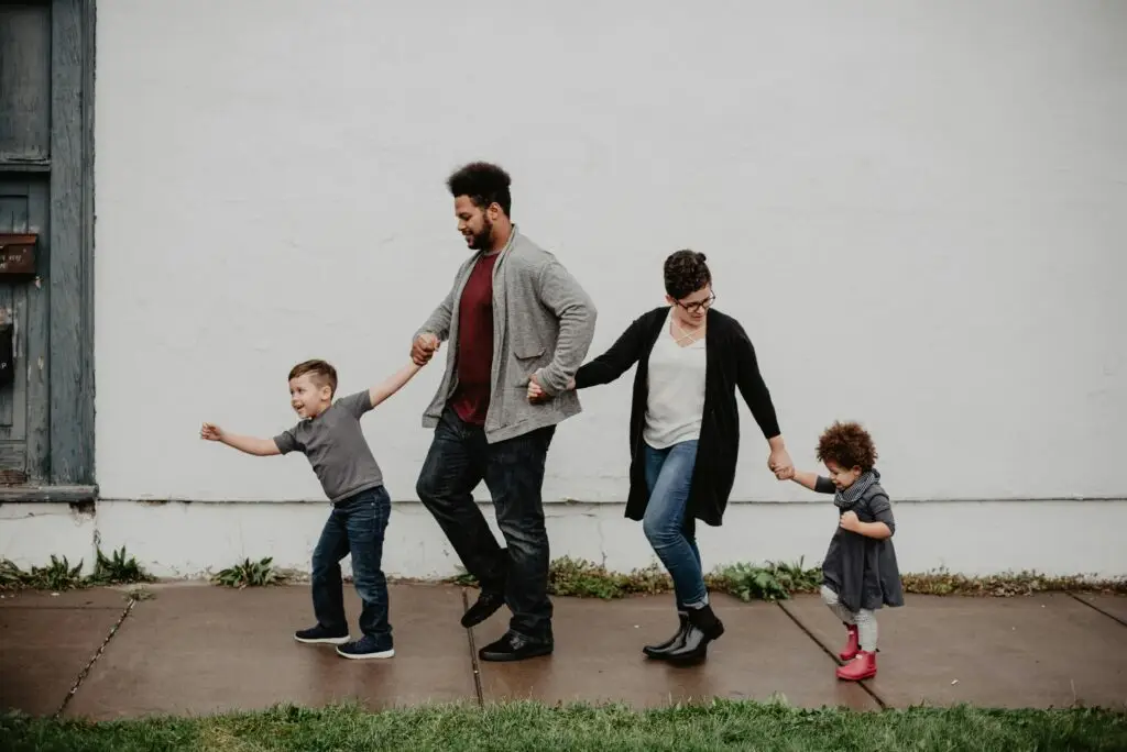 Compare Indexed Universal Life Insurance A joyful family walking together outdoors, holding hands in a playful and happy moment.
