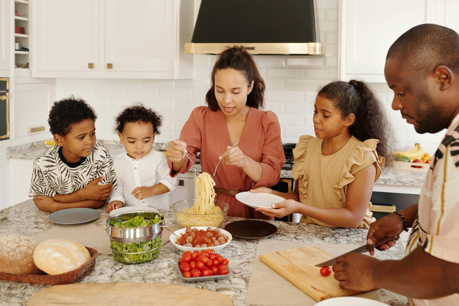 Home Family enjoying a cooking session together in a modern kitchen, preparing pasta and vegetables.