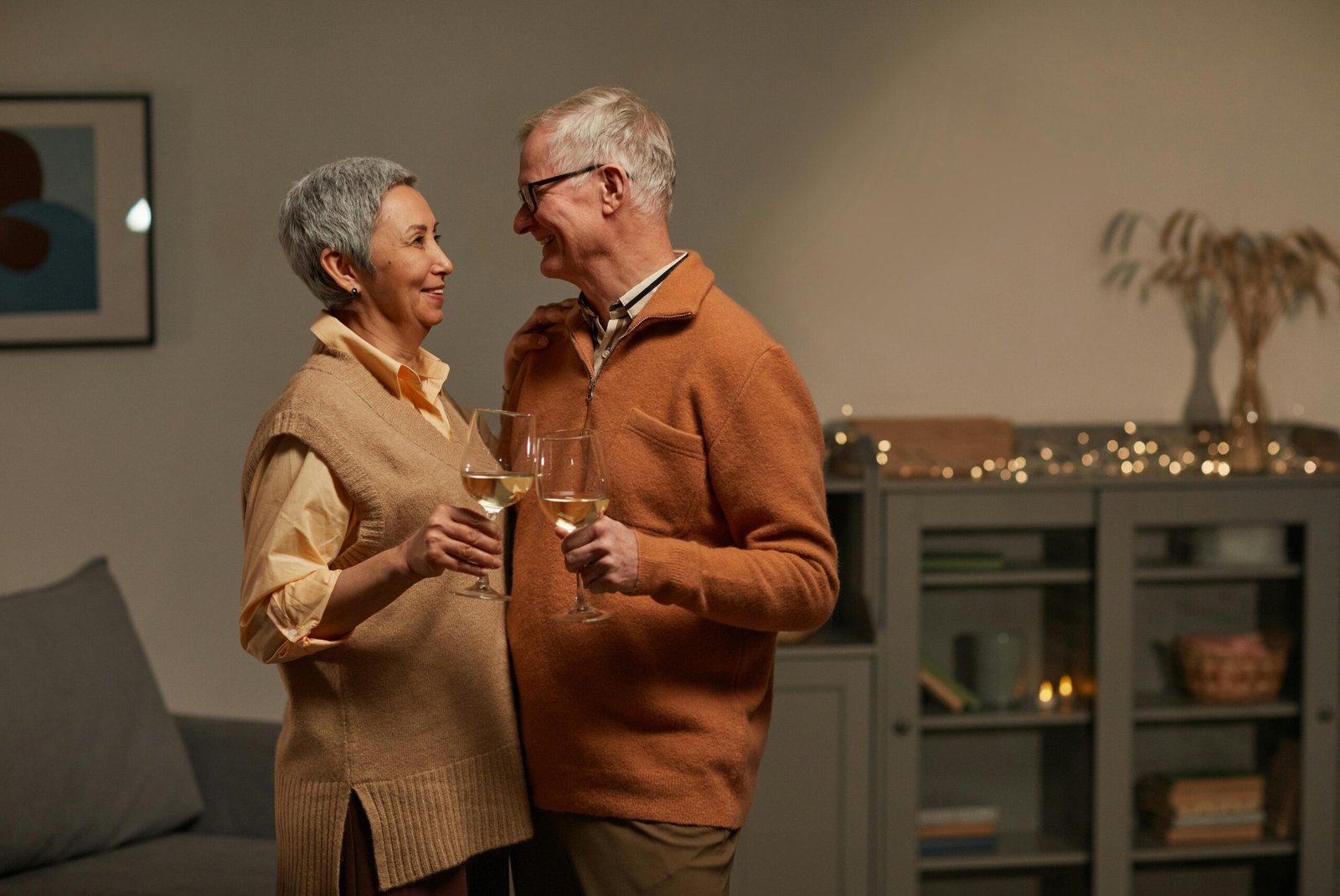 A joyful senior couple celebrating with wine glasses in a warm indoor setting.