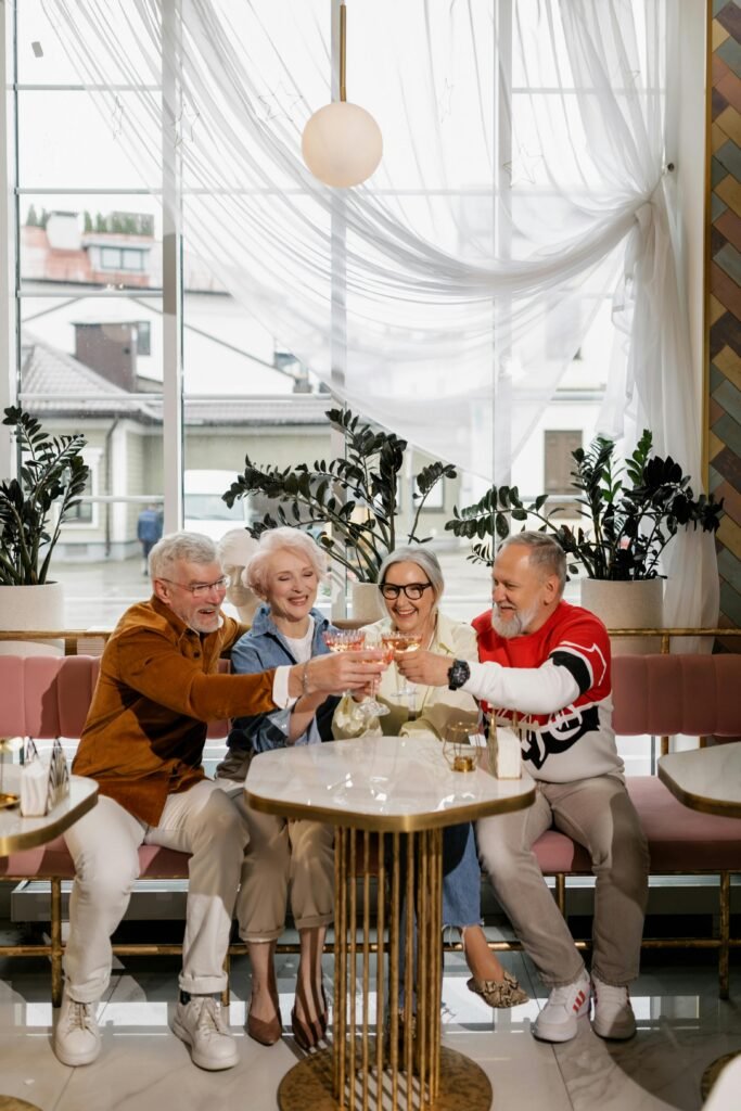 Coverage Options Elderly friends cheer with drinks in a chic café, celebrating togetherness and friendship.