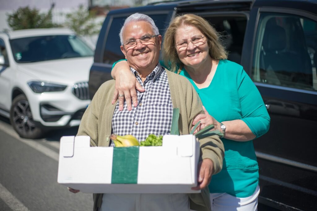 Elderly couple happily shopping with a grocery box outdoors in Portugal.